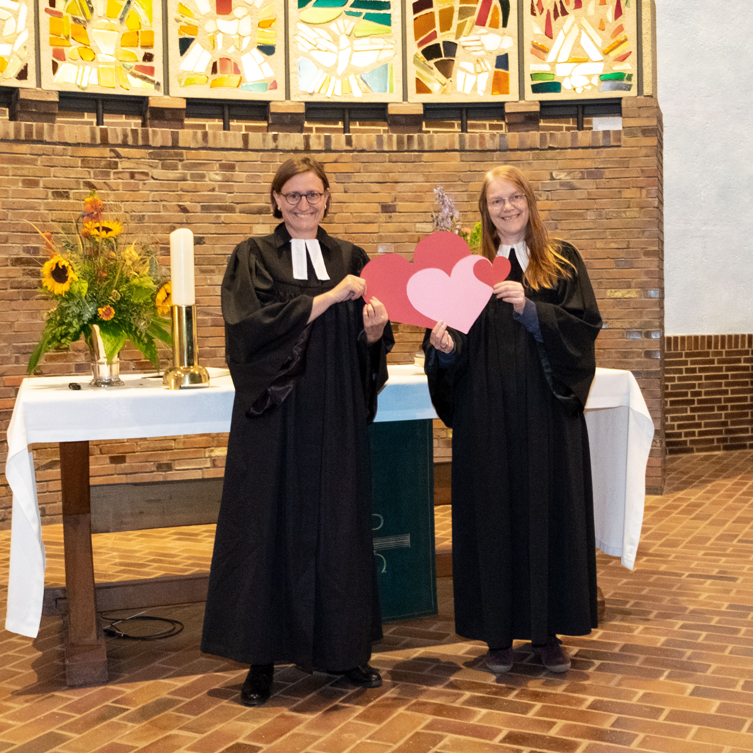 Pastorin Mirjam Kull und Pastorin Maike Windhorn-Stolte vor dem Altar der Anscharkirche