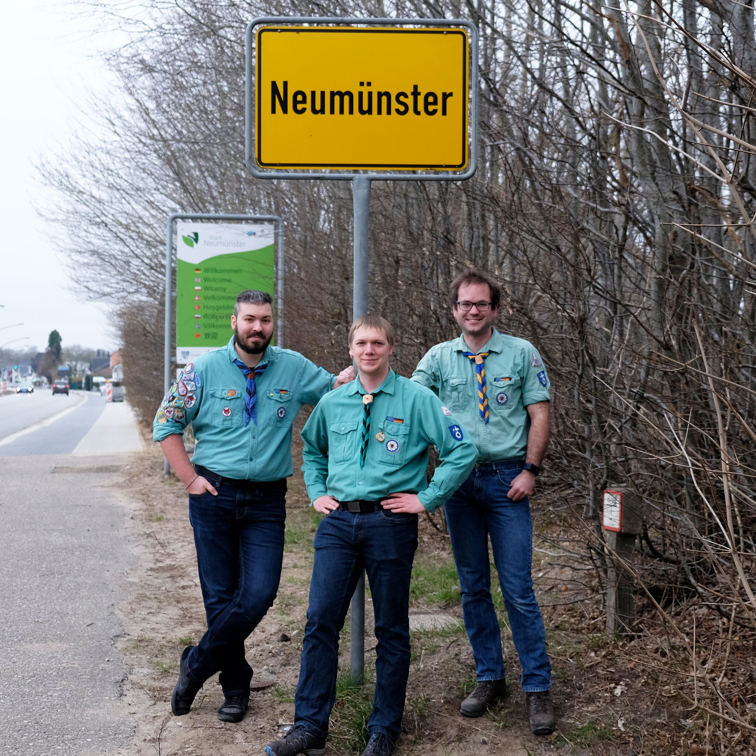 Marian Klüss, Torben Schlüter, Benedikt Merk vor dem Ortsschild Neumünster